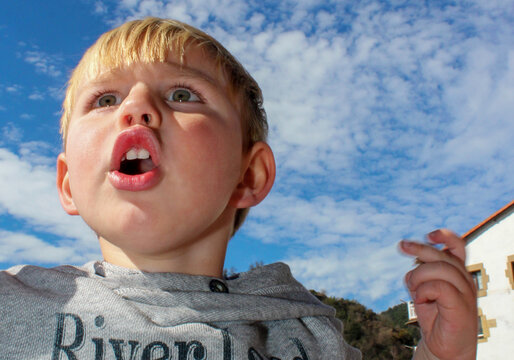 Retrato contrapicado de un ni&ntilde;o que grita con el cielo al fondo. Copyspace