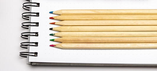 Obraz premium Notepad calculator lie on a white background writing space calculator keyboard colored wooden pencils