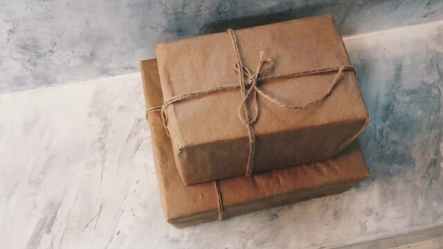 Packaged boxes for postal delivery service, parcels wrapped in brown paper and tied with rough twine in warehouse, concrete background with copyspace for design