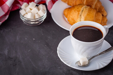 delicious fresh croissant and cup of coffee on a dark stone rustic background