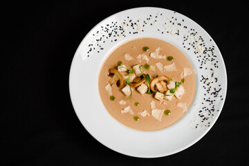 Creamy soup with mushrooms and croutons on black table