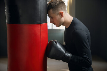 Tired boxer after training. A boxer stands by a punching bag. Workout in the gym. Sweaty athlete in the gym. 4k