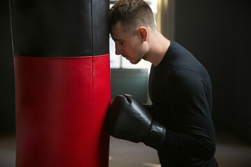 Tired boxer after training. A boxer stands by a punching bag. Workout in the gym. Sweaty athlete in the gym. 4k