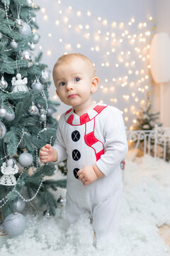 Little handsome boy in a snowman costume near the Christmas tree asks a question. lights, new year card, picture