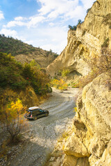 Aerial low angle view of 4X4 drive car turning left in scenic valley with rocky cliffs around