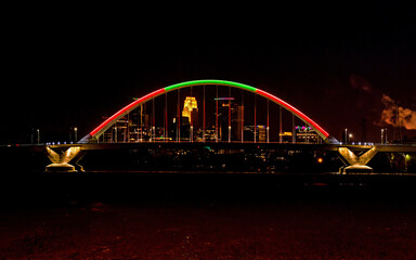 Lowry Avenue Bridge colored red and green at dusk on Christmas day with Minneapolis Skyline behind	