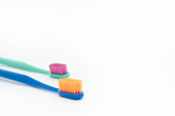 Two colored toothbrushes with bright bristles on a white background close-up on the left