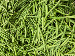 Big pile of organic green beans and farmers market grocers fresh produce stand