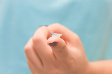 Contact lens on human hand on blue background. Selective focus. Close up