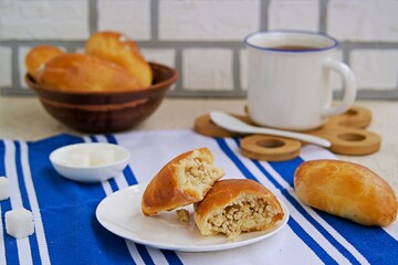 Homemade baked pies from yeast dough with meat on a white plate on a light concrete background. Russian kitchen.