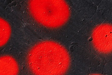 Black concrete wall with bright red round spots of paint. Empty background.	