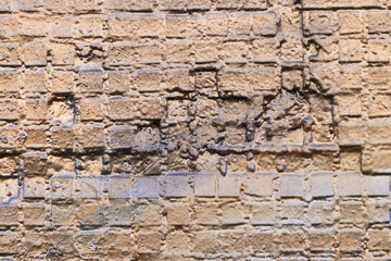 Old brick wall covered with beige and gold paint. Empty background. Close-up.