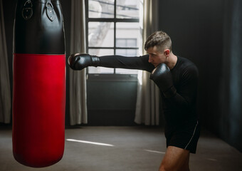 A young athletic man is hitting a boxing bag. Boxer practicing punches in the ring. The athlete...