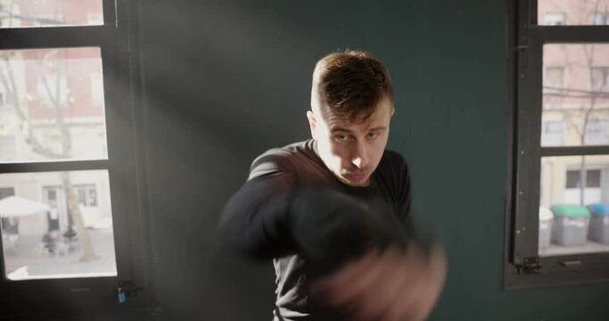 The man is an athlete boxing in the gym. Boxer practicing punches in the ring. Shadow-boxing. The athlete strikes with a punching bag. 4k video