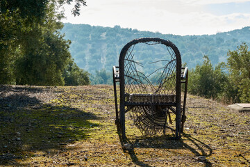 Abandoned broken wicker chair in the field overlooking the olive grove