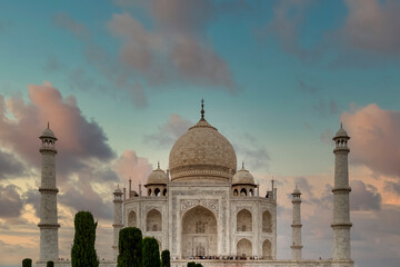 Fototapeta na wymiar The famous Taj Mahal under a beautiful sky with clouds colored by the delicate hues of the sunset, Agra, India