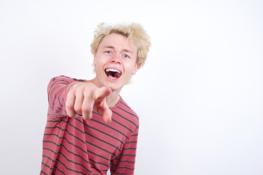 Young handsome Caucasian blond man standing against white background pointing displeased and frustrated to the camera, angry and furious ready to fight with you.