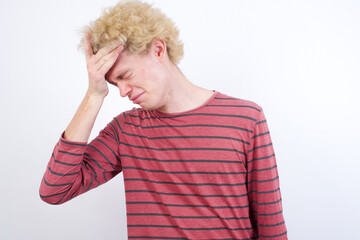 A very upset and lonely Young handsome Caucasian blond man standing against white background crying,