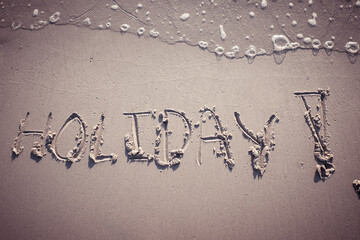word HOLIDAY written on the sand