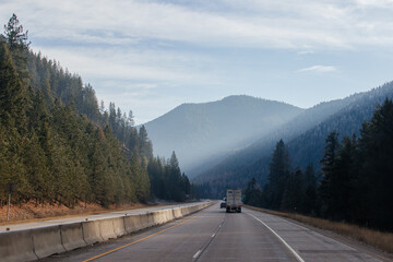 Highway with road signs on the sides among high mountains in the clouds in winter, along which...