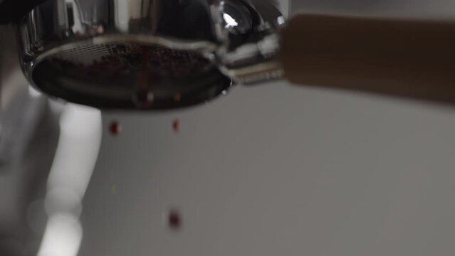 Slow motion low angle bad shot of espresso extraction from naked portafilter into white cup