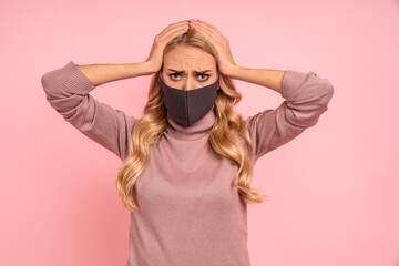 Worried young blonde girl in pink blouse, sterile face mask isolated on pink background. Epidemic pandemic rapidly spreading coronavirus SARS-CoV-2 covid-19 flu virus concept. Put hands on head