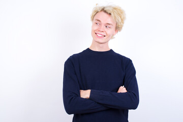 Dreamy rest relaxed Young handsome Caucasian blond man standing against white background crossing arms, looks good copyspace