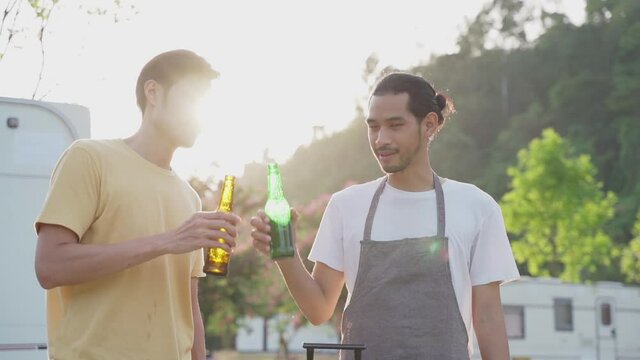 Two travelers clinking beer bottles and show to camera on holiday trip