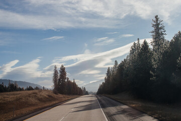 An asphalt road along which cars and trucks go, among the mountains, ahead on the horizon mountains in fog, the sky is covered with clouds. Idaho, USA, 11-23-2019