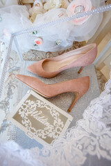 Women's peach shoes. Nearby on the veil are the wedding rings of the bride and groom.