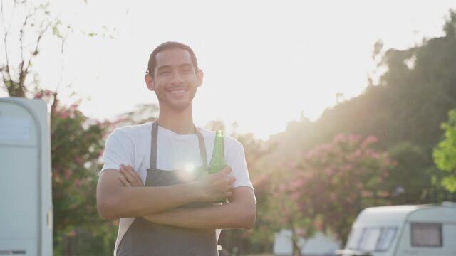 Smiling traveler show green bottle of beer to camera on holiday trip
