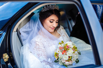 beautiful bride with a bouquet of roses sitting in the car

