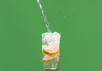 refreshing glass of watter with lemon, lemmonade been served against green backgound
