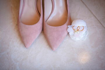 Women's peach shoes. Nearby on the veil are the wedding rings of the bride and groom.