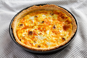 Homemade Bacon Quiche with Eggs and Cheddar Cheese on cloth, low angle view.