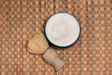 Shaving cream and shaving brush on wicker background