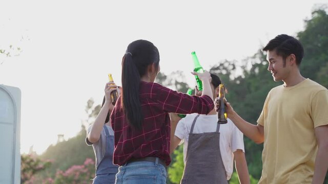Friend clinking and drinking bottles of beer with happiness and smile.