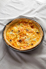 Homemade Bacon Quiche with Eggs and Cheddar Cheese on cloth, side view.