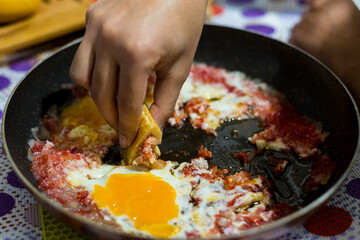 The hand of the young man who eats bread and eggs (menemen)