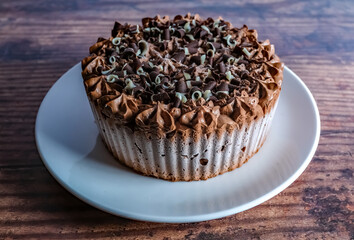 Norwich, Norfolk, UK – December 25 2020. An illustrative editorial photograph of a close up of a double chocolate gateau on a white plate on a wooden top