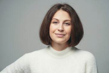 close up portrait of a smiling young brunette woman of Caucasian appearance. looking at the camera, posing in a photo studio on a gray background. banner copy space