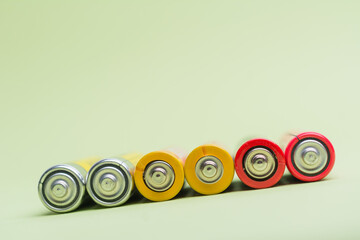 Spent batteries stacked in a row isolated on a green background.