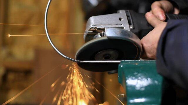 Selective focus of female hand, holding and using hand welding machine to join pipe pieces on circular mark while holding rod with clamp in workspace