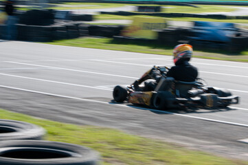 Unrecognised man driving Go-kart with speed in the on a karting track - obrazy, fototapety, plakaty