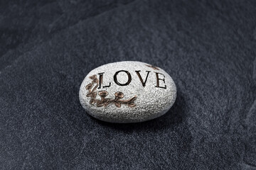 Stone with text on a dark background. Close-up. Copy space.