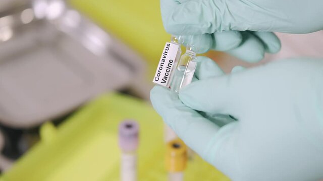 Vaccination concept. Doctor is going to do covid-19 vaccination to a patient. She is opening the ampula.