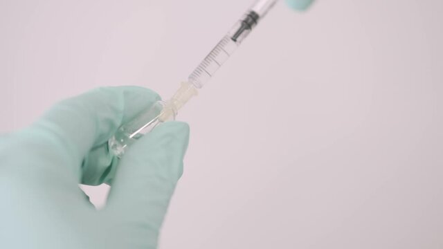 Vaccination concept. Doctor is going to do covid-19 vaccination to a patient. She is opening the ampula.