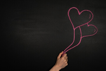 Zwei Herzförmige Luftballons in der Hand, gezeichnet auf dem schwarzen Kreidetafel