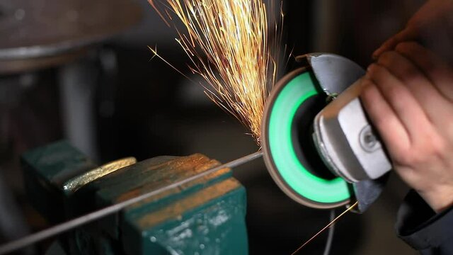 Selective focus of female blacksmith using electrical hand welding machine to join iron rod in a circular shape and polish it during welding process