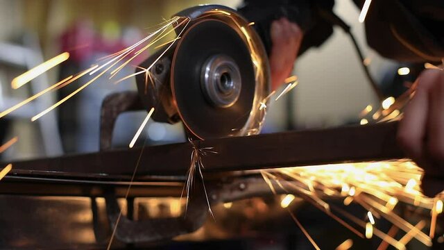 Selective focus of young woman, using grinding machine to cut metal rod pipes in pieces with firm hold using clamp as per requirement on workspace